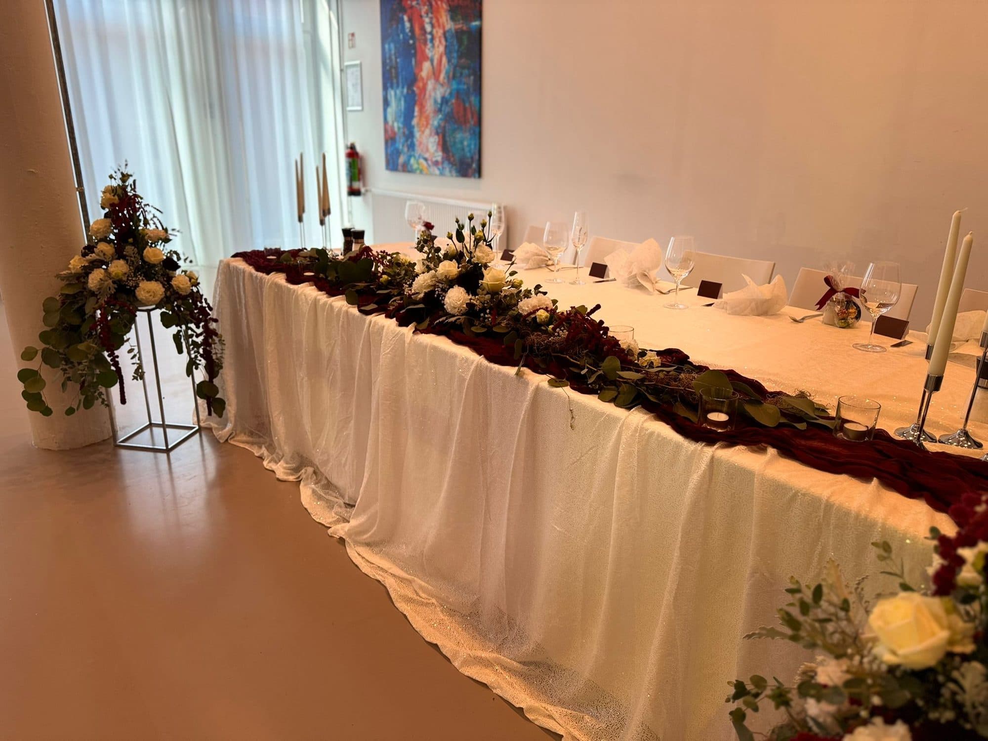 Lange weiße Tafel mit Blumenläufer und Kerzen in der Eventlocation REST2RENT Hamburg