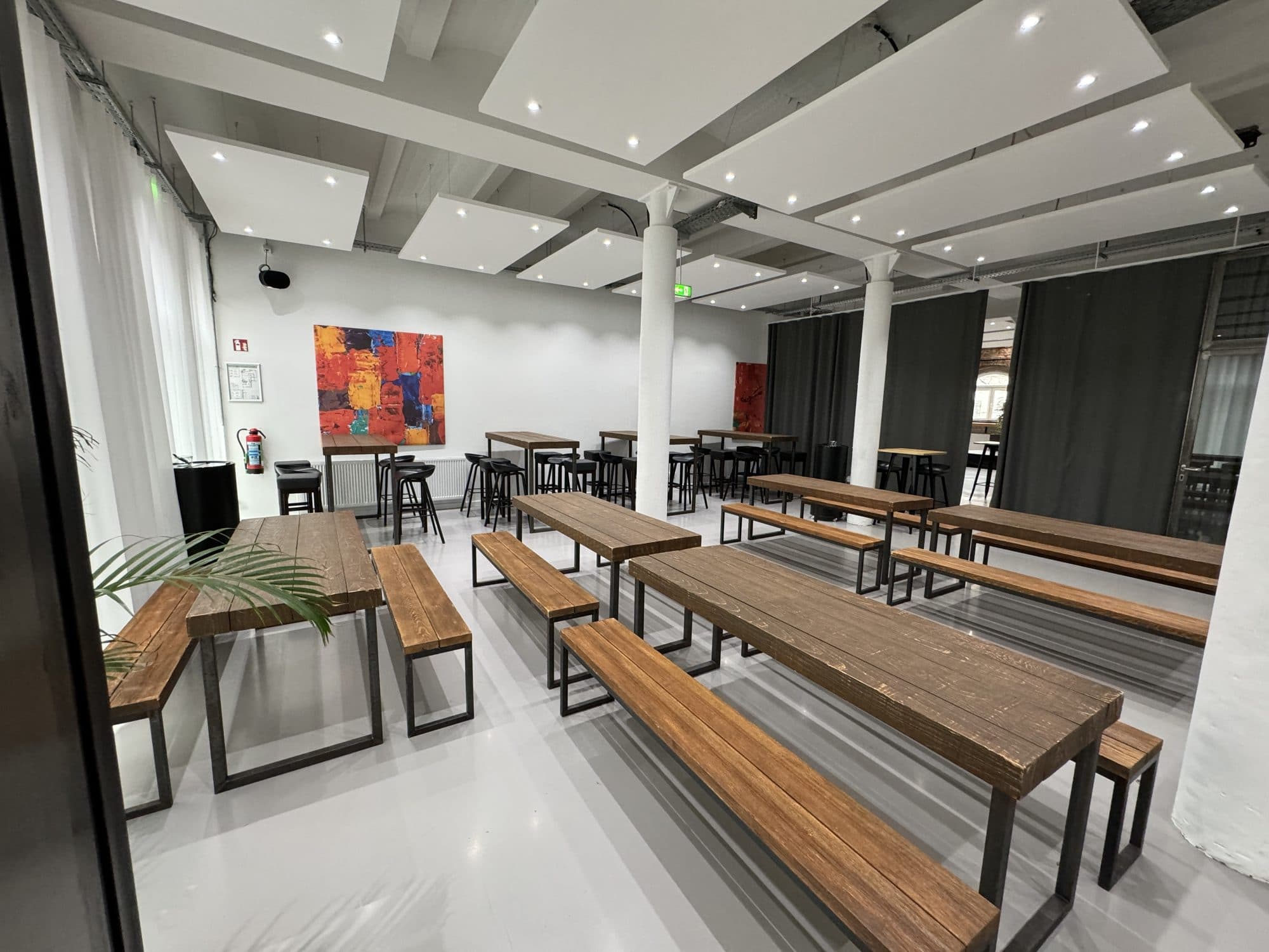 Holztische mit Bänken im hellen Loft in der Eventlocation REST2RENT Hamburg