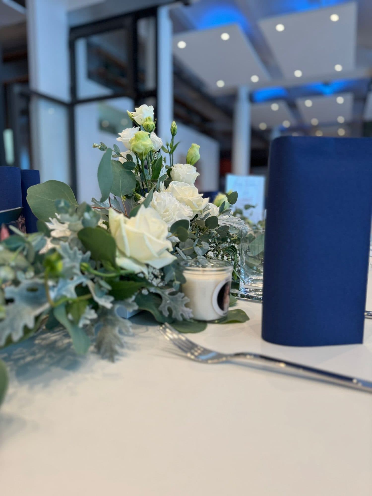 Tischdeko mit weißen Blumen und blauer Serviette in der Eventlocation REST2RENT Hamburg