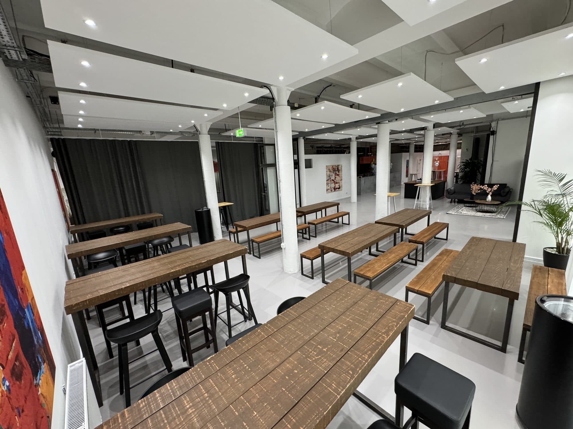 Reihen von Holztischen und Bänken in der Eventlocation REST2RENT Hamburg