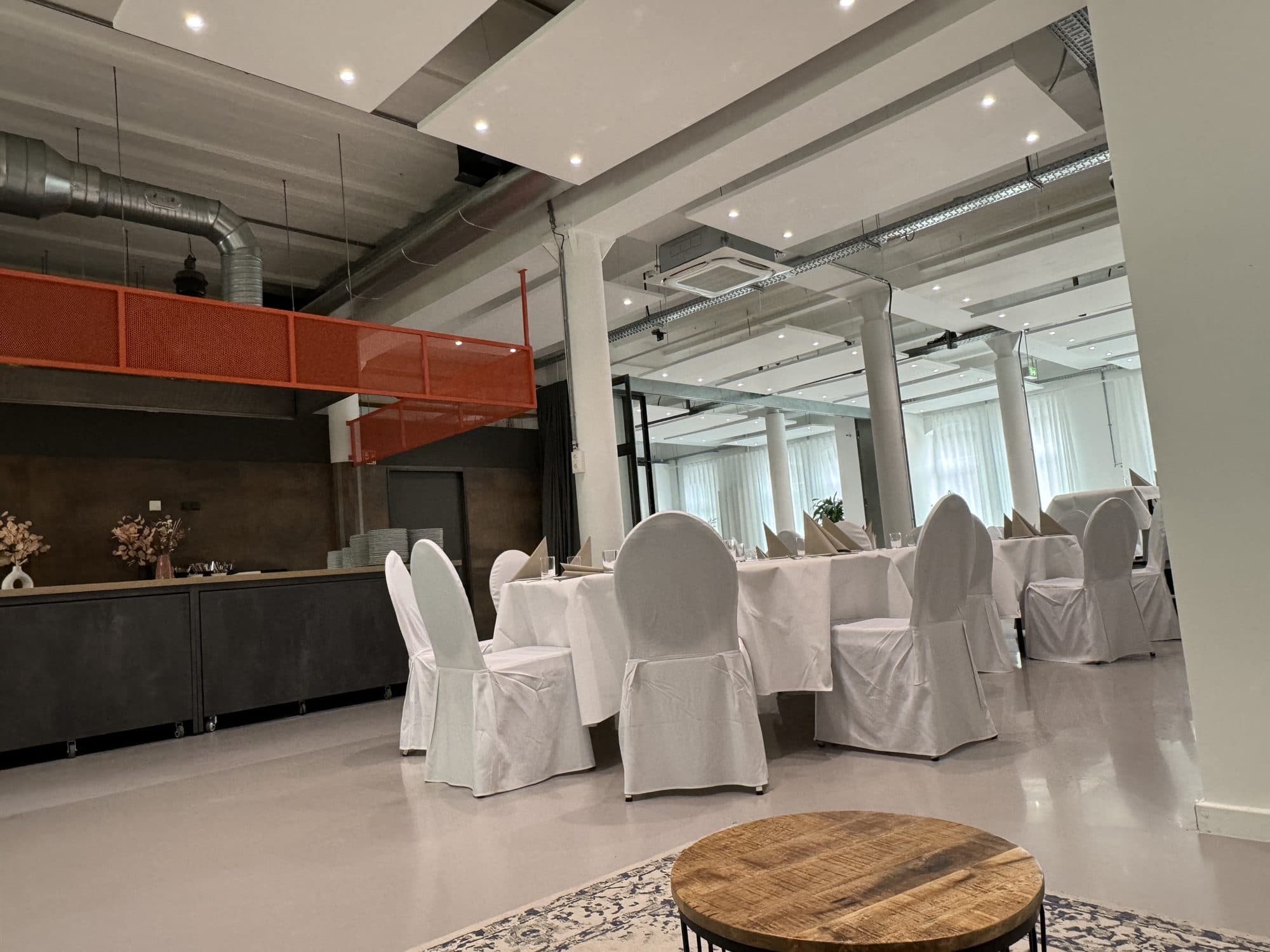 Runde Tische mit weißen Hussen vor der Kitchen Area in der Eventlocation REST2RENT Hamburg