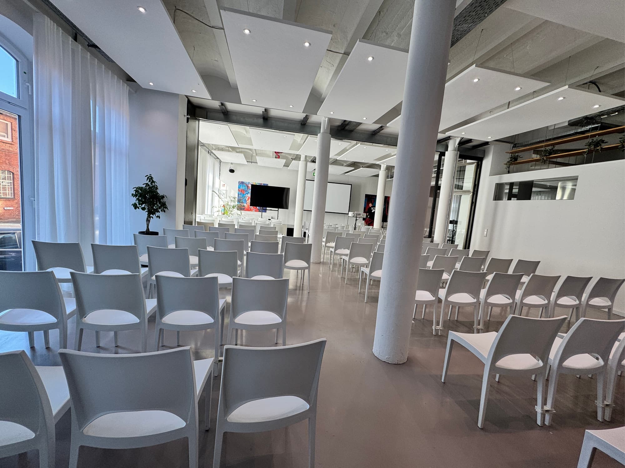 Conference seating in rows between white columns, daylight through lattice windows – corporate events at REST2RENT Hamburg